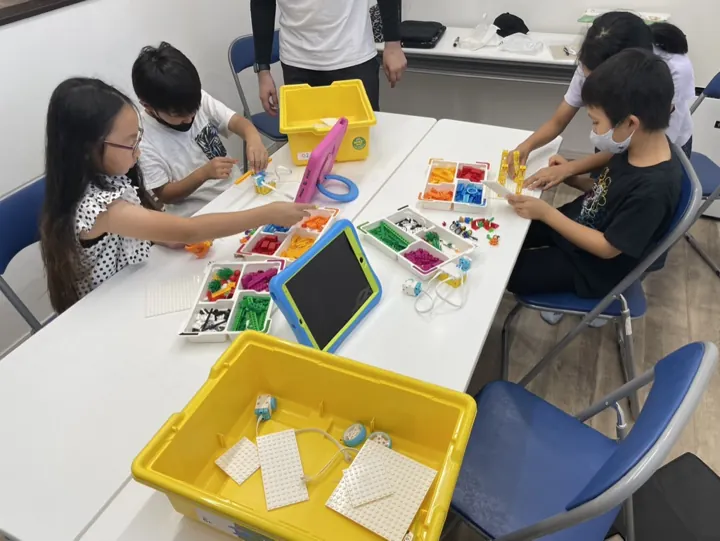 姫路の子ども向けSTEAM|英語で学ぶものづくり|ワンダーランド 5 タブレットを見ながら、ブロックの組み立てに取り組む子どもたち